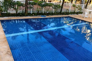 A clear blue pool with a tiled edge and a white fence in the background. - Reserva do Sahy, Condado (Mangaratiba)