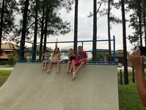 A concrete ramp with a blue metal railing, surrounded by trees and residential buildings. - Reserva do Sahy, Condado (Mangaratiba)