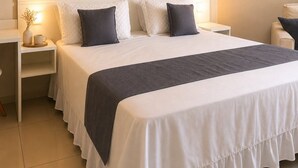 Cama bem arrumada com cabeceira branca e manta cinza escura.