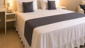 Ein ordentlich bezogenes Bett mit einem weißen Kopfteil und einer dunkelgrauen Decke.