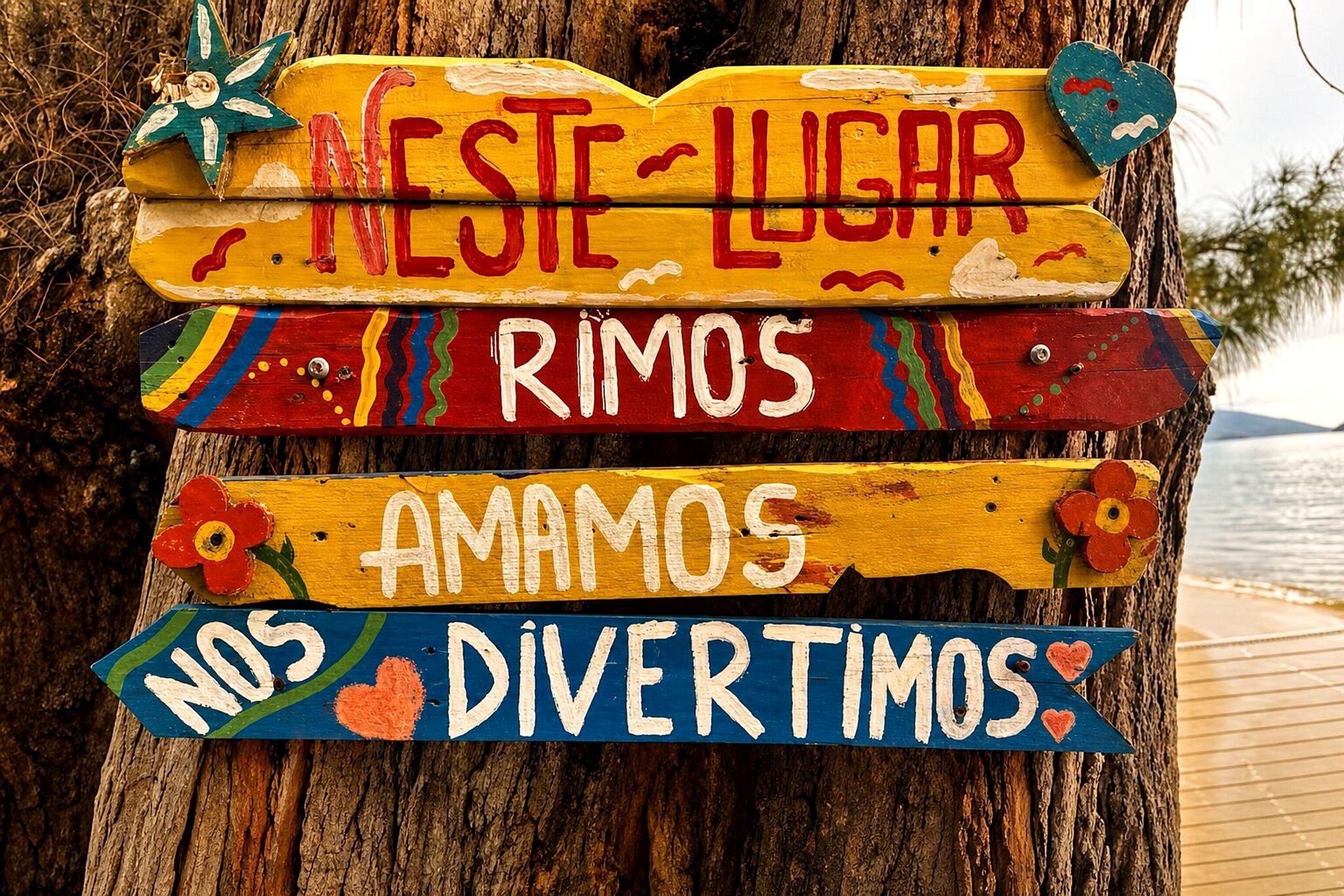 A wooden sign with colorful text and decorations, attached to a tree.