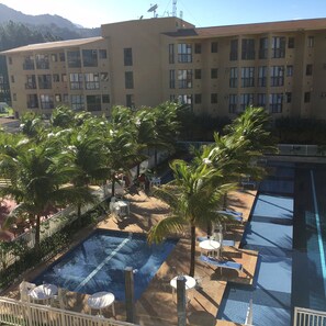 A hotel with a swimming pool, palm trees, and a view of a mountain. - Reserva do Sahy, Condado (Mangaratiba)