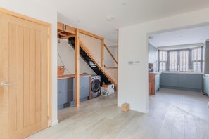A modern kitchen with a built-in washing machine, a staircase leading to an upper level, and a large window providing natural light. - Homely and Spacious 3BD Home in Islington (London)