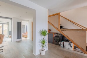 A modern apartment with a wooden staircase, a washing machine, and a potted plant. - Homely and Spacious 3BD Home in Islington (London)