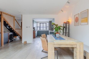 A modern apartment with a dining area, kitchen, and a staircase leading to an upper floor.