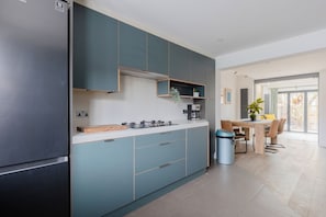 A modern kitchen with a built-in stove, a coffee machine, and a trash bin.