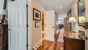 A hallway with white doors, a wooden floor, and a rug leading to a living area. - Stone Creek Meadows 205 2 Bedroom Condo (Avon)