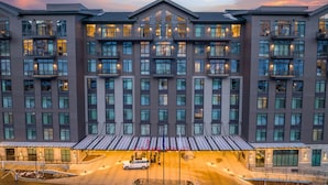 Een hotel met meerdere verdiepingen, een centraal atrium, grote ramen en een overdekt entreegebied.