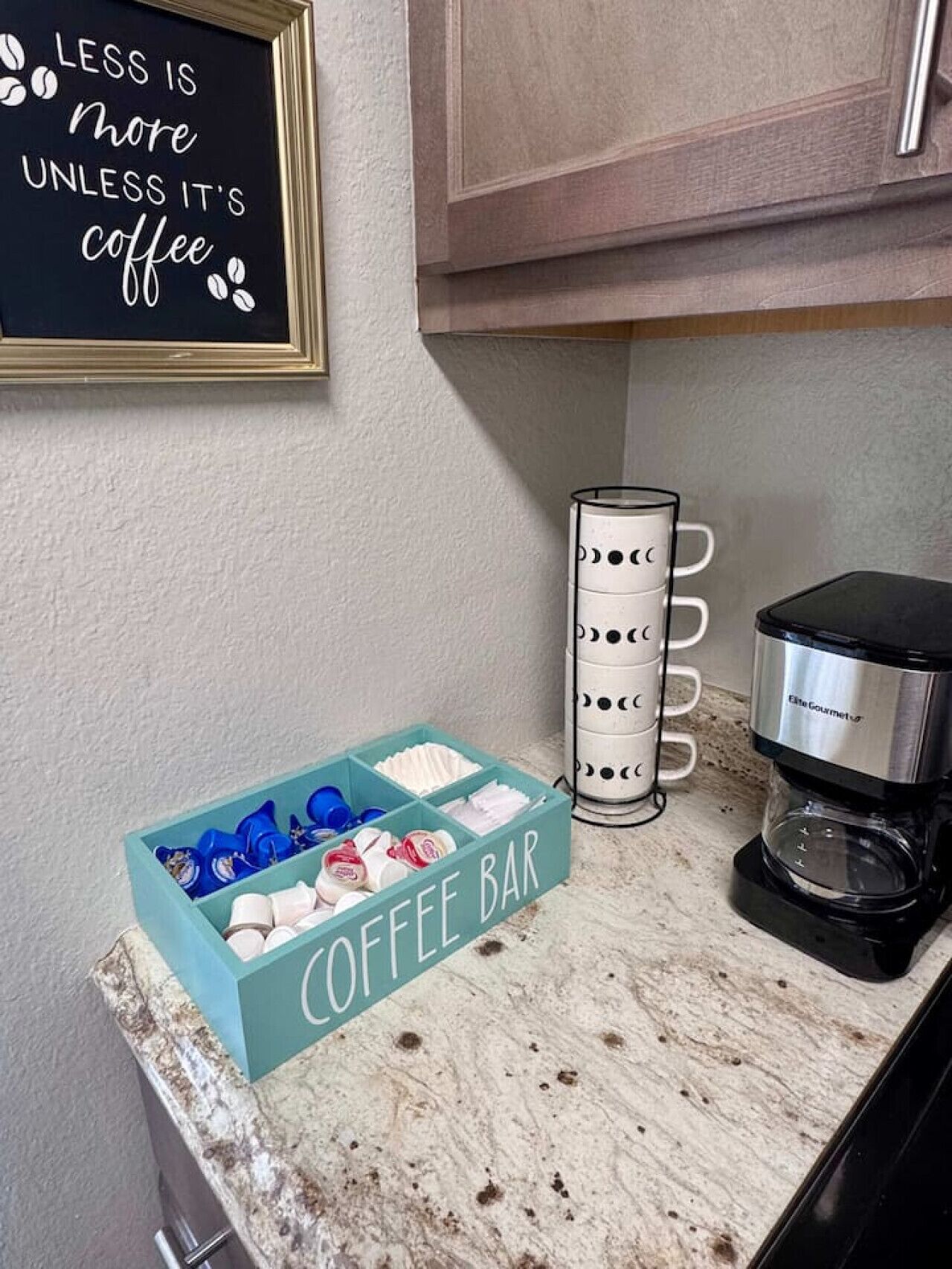 Eine Küchenarbeitsplatte mit einer Kaffeebar, einer Kaffeemaschine und einem Schild mit der Aufschrift 'LESS IS MORE UNLESS IT'S COFFEE'.