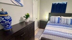 A bedroom with a bed, a dresser, a nightstand, a potted plant, and a decorative vase. - Comfy 2BR 1BA Apt (Nederland)