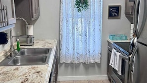 A kitchen with a stainless steel refrigerator, a double sink, and a countertop with a coffee bar. - Comfy 2BR 1BA Apt (Nederland)