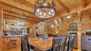A wooden cabin interior with a dining area, kitchen, and living space. - Chillin N Grillin 2 Bedroom Cabin (Sevierville)