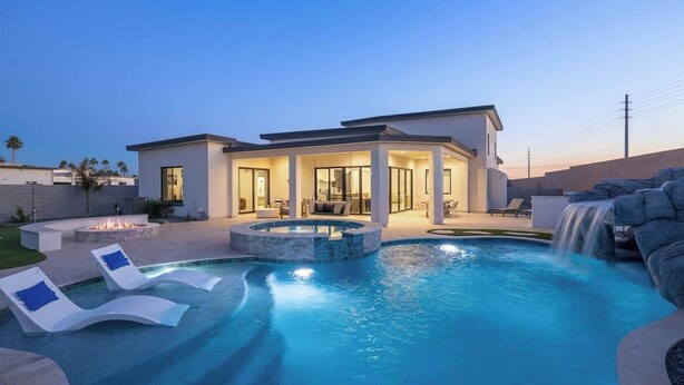 A modern house with a swimming pool, lounge chairs, and a waterfall feature. - Luxury Lounge - 5BR, Pool&Spa, Sauna, Firepit (Scottsdale)