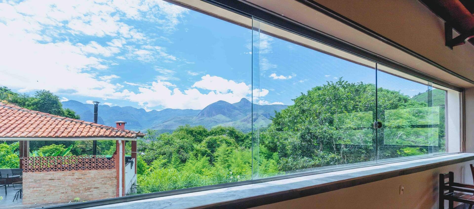 A room with a large window offering a view of a mountainous landscape and lush greenery.