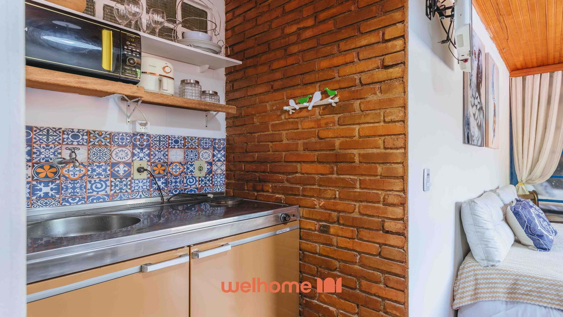 Une cuisine compacte avec un mur en briques, un pare-feu en carreaux et un lit donnant sur une fenêtre.