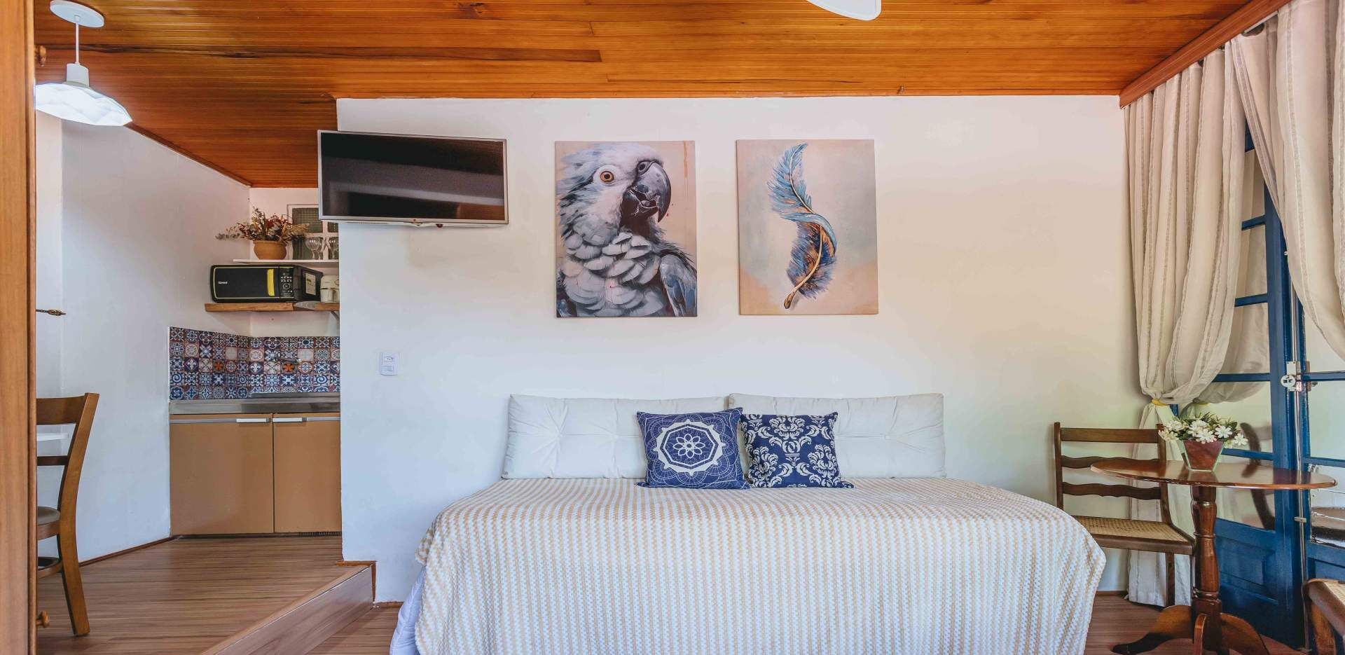 A bedroom with a bed, two pillows, a TV on the wall, and artwork.