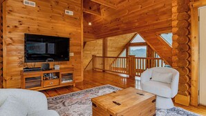Een houten cabin met een televisie, bank en een houten kist.