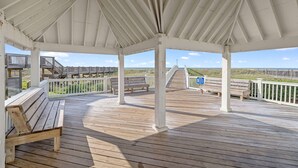 Una terraza cubierta de madera con bancos y vista al mar.