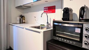 Una cocina compacta equipada con microondas, tostadora y lavabo.
