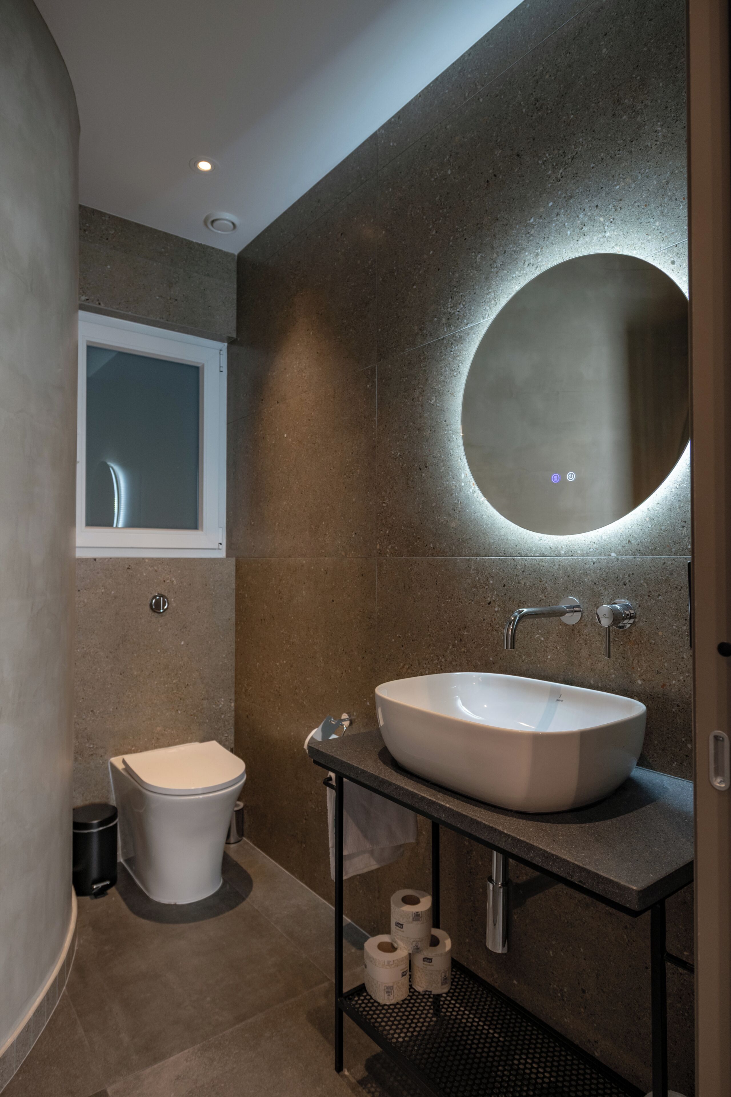 Un baño moderno con inodoro, lavamanos y espejo.