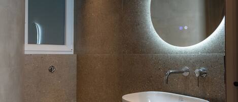 Un baño moderno con inodoro, lavamanos y espejo.