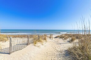 A sandy beach with a wooden fence leading to the water.