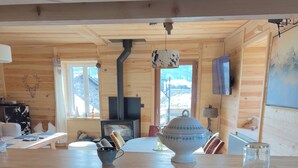 Tunnelmallinen, puinen mökki, jonka sisätiloissa on keittiö, jossa on pesuallas, liesi ja ruokapöytä.