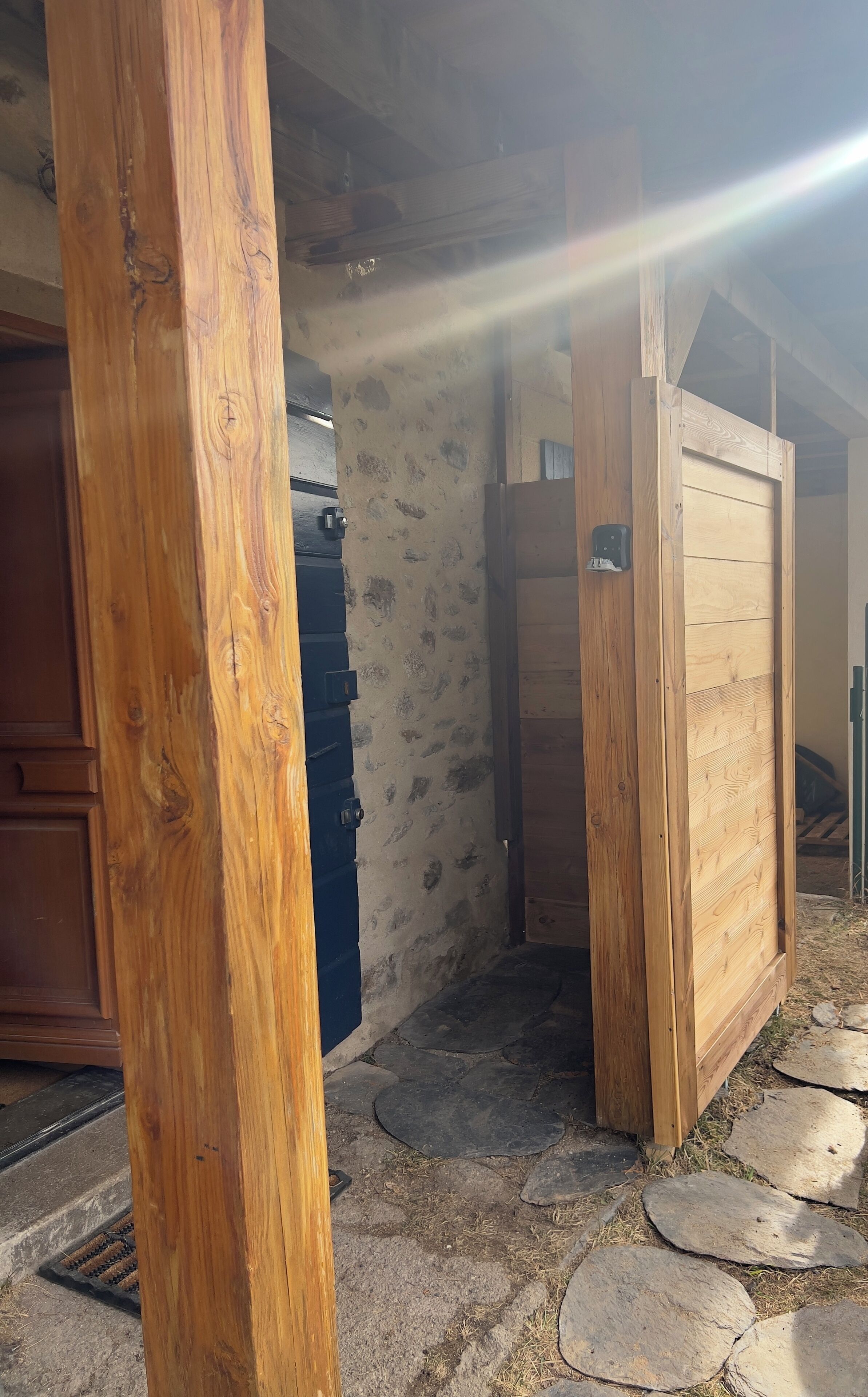Une porte en bois rustique, un mur en pierre et une sonnette en métal.