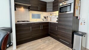 A compact kitchen with dark wood cabinets, a stainless steel oven, and a microwave.