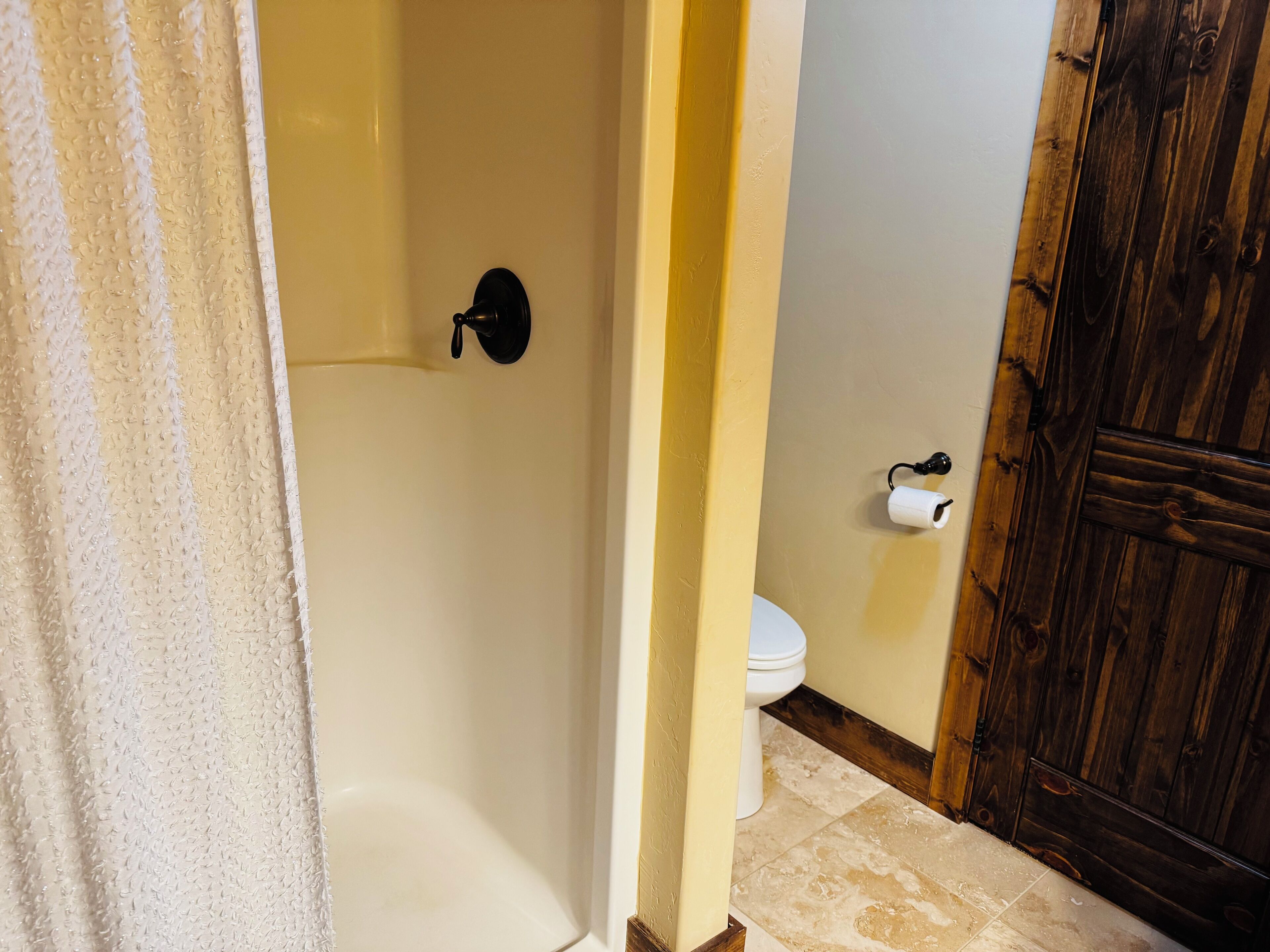 A bathroom with a bathtub, toilet, and wooden door.