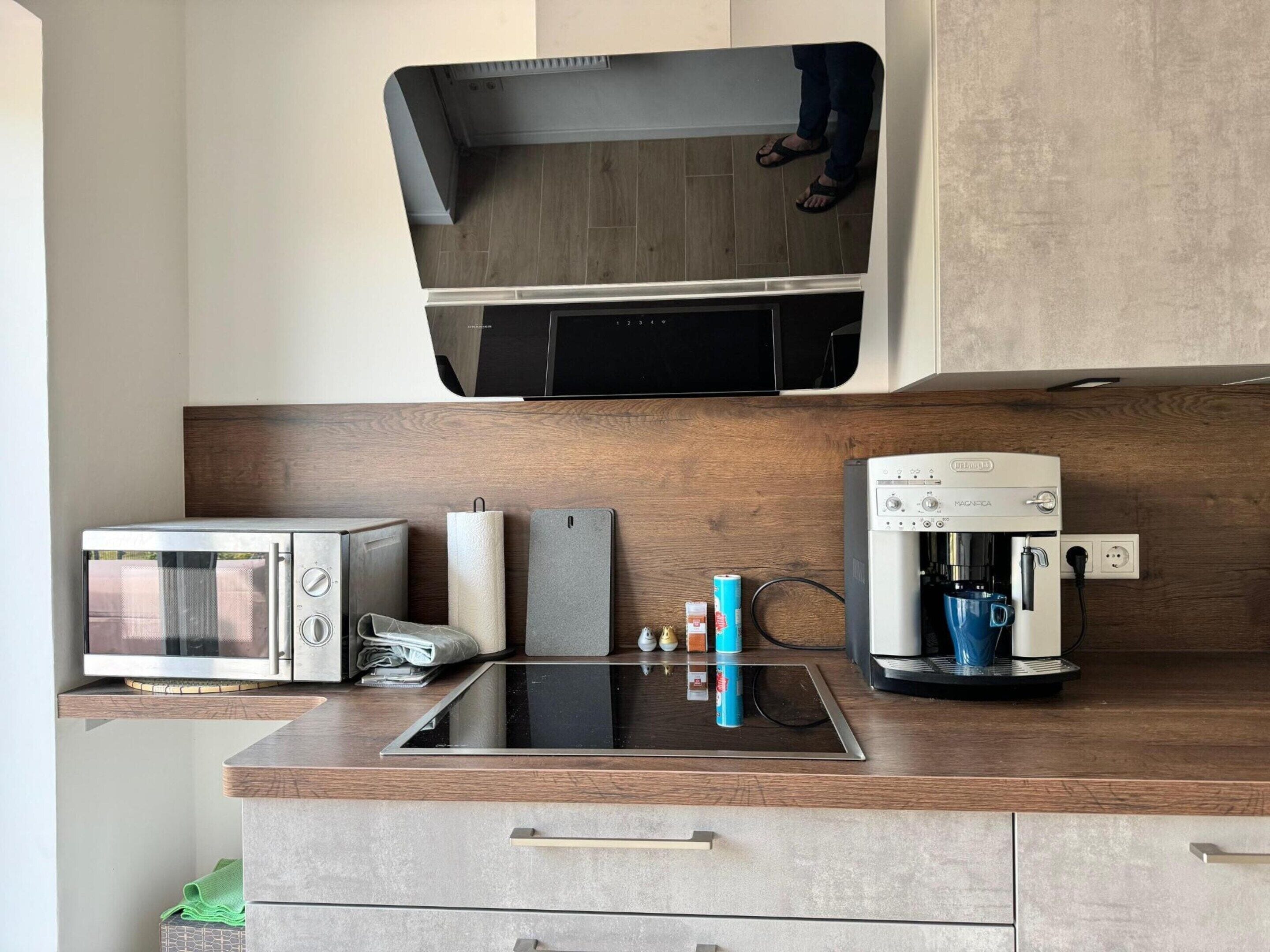 Cozinha equipada com micro-ondas embutido, cafeteira e televisão de tela plana fixada acima do balcão.