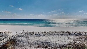 A beach with a clear sky and calm sea. There are no visible buildings or structures.