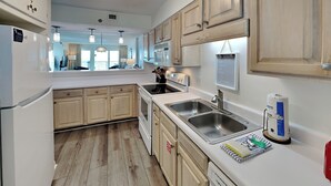 A modern kitchen with wooden cabinets, stainless steel appliances, and a large window providing natural light.