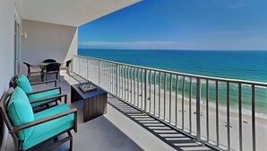 Un balcon avec vue sur l’océan, une table et deux chaises.