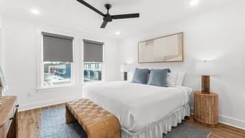 Un dormitorio con cama, un banco, una lámpara de pie y un ventilador de techo.