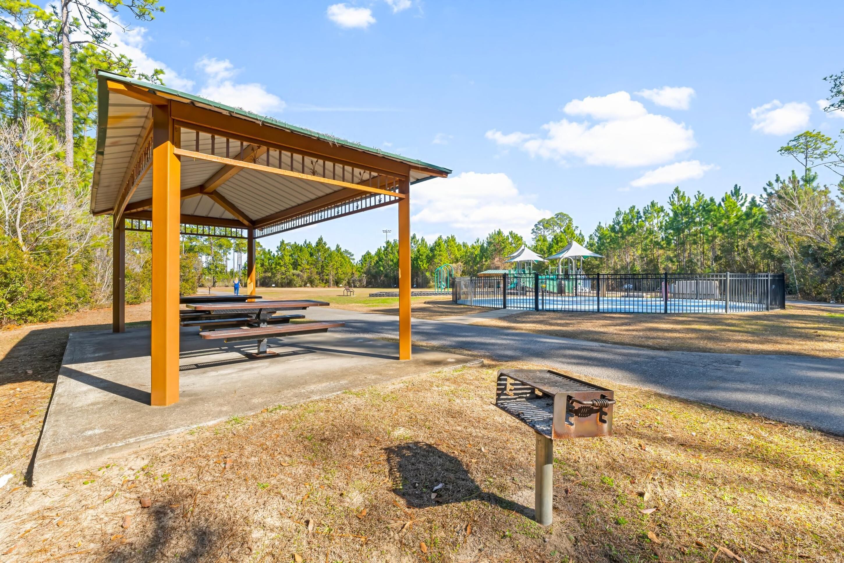 Un área de picnic techada con bancos y un parque infantil.