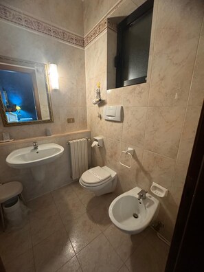 A bathroom with two sinks, a toilet, a bidet, and a mirror.