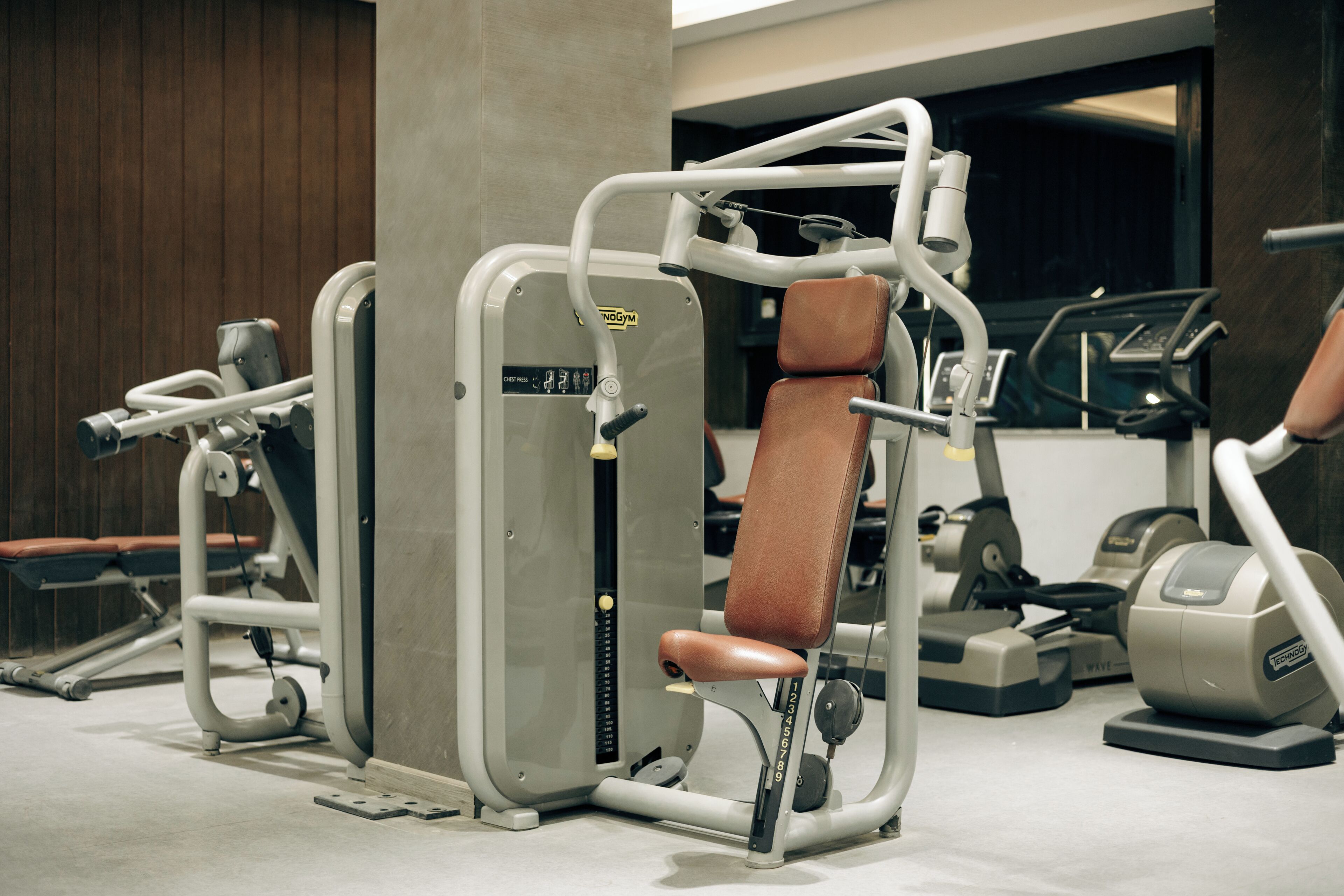 A gym with exercise machines, a weight bench, and a wall-mounted mirror.