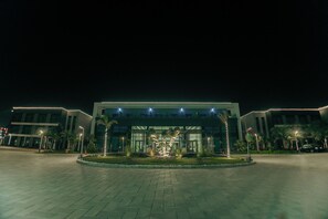 A modern building with a paved entrance area, a well-lit entrance, and a landscaped garden. - Phoenix Hotel and Wellness (6th of October City)
