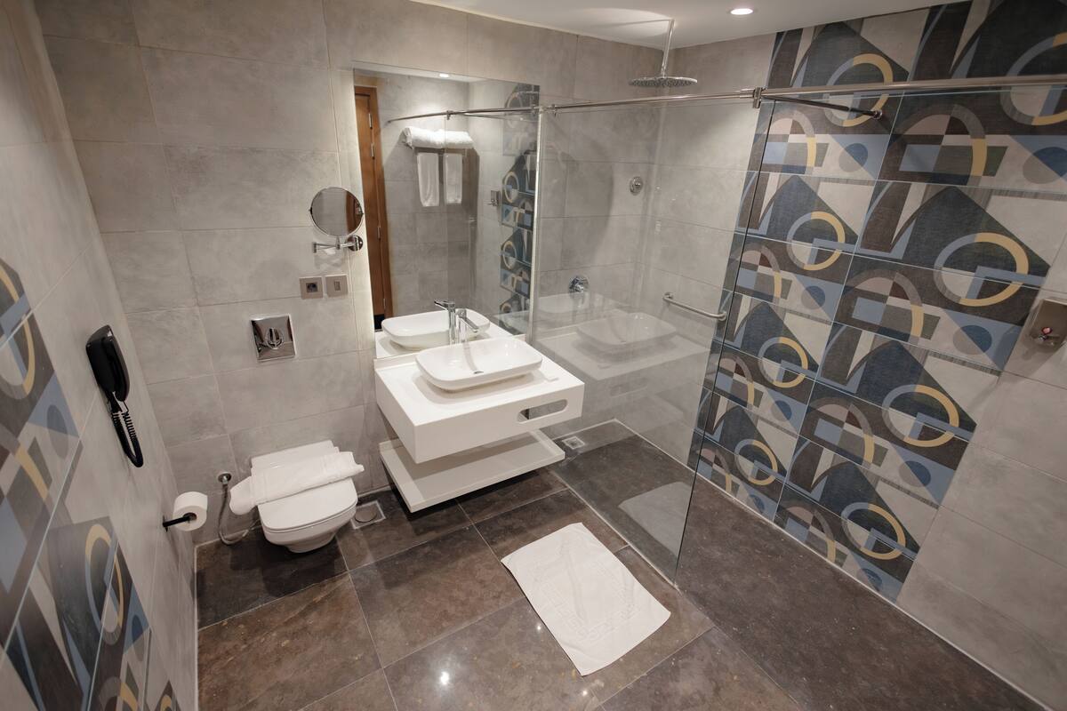 A modern bathroom with a glass shower enclosure, a white sink, and a toilet.