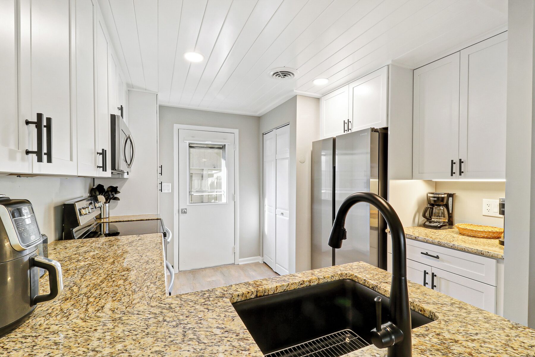 A modern kitchen with granite countertops, stainless steel appliances, and white cabinetry.