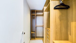 A walk-in closet with wooden shelving, drawers, and hanging space. - Generous Covent Garden Apartment (London)
