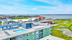 A hotel with a rooftop pool, multiple balconies, and a view of the sea.