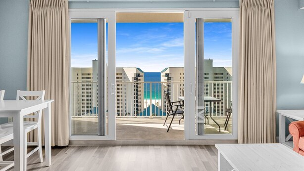 A modern room with a balcony, a dining table, and a sofa. - Gulf View Laketown Wharf 1BR/2BA condo unit 1013 (Panama City Beach)