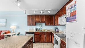 A kitchen with wooden cabinets, a granite countertop, a microwave, a refrigerator, and a sink. - Gulf View Laketown Wharf 1BR/2BA condo unit 1013 (Panama City Beach)