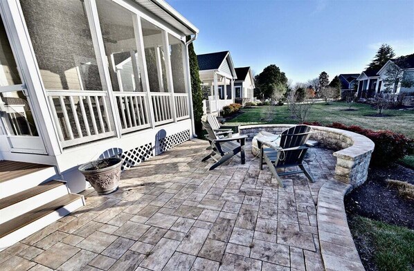 A covered patio with outdoor furniture, a stone planter, and a view of a residential neighborhood.