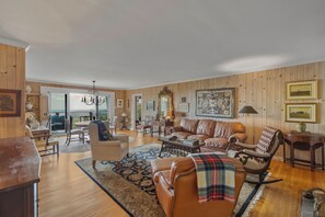 Un amplio salón con un ventanal grande, chimenea y comedor con vistas.