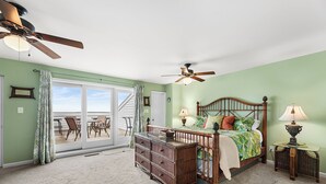 A bedroom with a large bed, a dresser, two nightstands, a ceiling fan, and a view of the beach through a sliding glass door. - Midtown , 3 bedroom, 3 bathroom, 2 level condo, close to the beach (Ocean City)