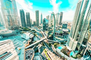A modern cityscape with high-rise buildings, a prominent curved structure, and a complex road network. - Burj View Studio Downtown (Dubai)