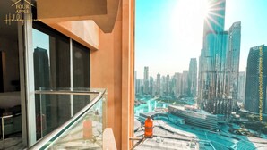 A balcony with a glass railing overlooking a modern cityscape with high-rise buildings and a curved road. - Burj View Studio Downtown (Dubai)